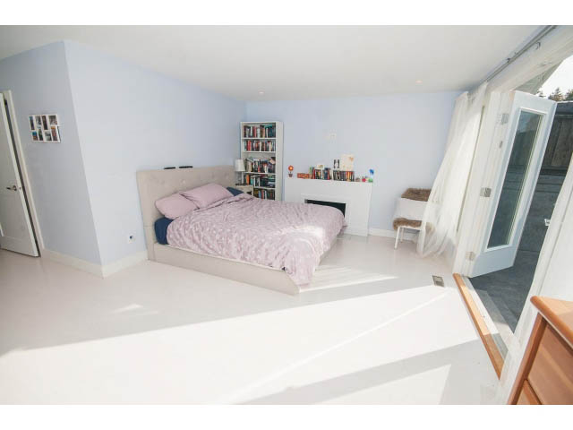 Bright bedroom with white walls, wooden floors, and a large window. - 389 Beachview Dr, North Vancouver