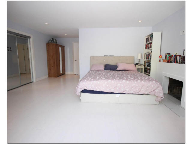 Spacious bedroom with white walls, large bed, and bookshelf. - 389 Beachview Dr, North Vancouver