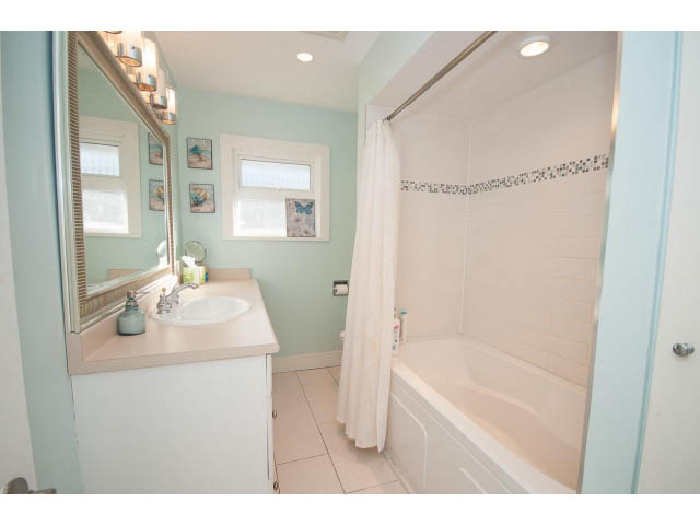 Bathroom with light blue walls, white vanity, and a bathtub with a shower curtain. - 389 Beachview Dr, North Vancouver