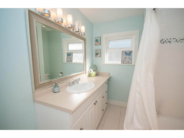 Bright bathroom with light blue walls, white countertop, and butterfly decor. - 389 Beachview Dr, North Vancouver