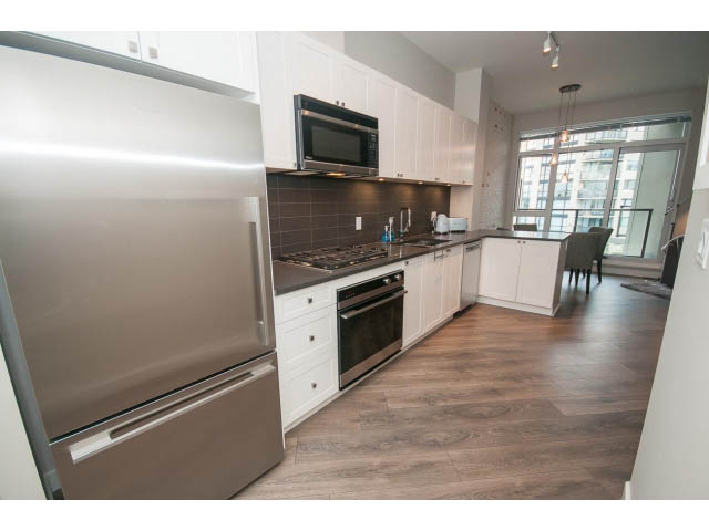 Bright kitchen with stainless steel appliances, hardwood floors, and a city view. - 405 - 105 West 2nd St, North Vancouver