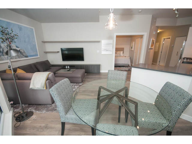 Furnished living room with modern furniture, glass coffee table, and a flat-screen TV. - 405 - 105 West 2nd St, North Vancouver