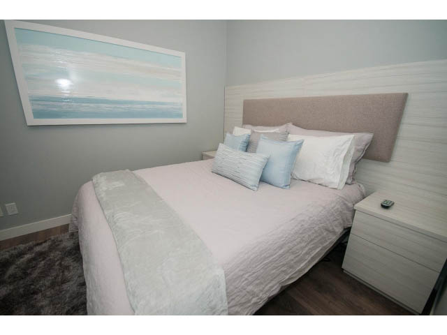 Furnished 1-bedroom condo with modern decor, light grey walls, and a large bed with white and light blue bedding.