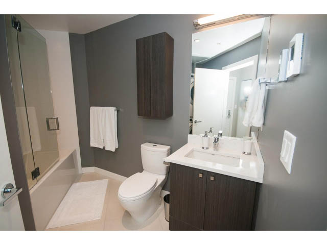Furnished 1-bedroom condo bathroom with modern sink, toilet, and glass shower. - 405 - 105 West 2nd St, North Vancouver