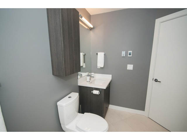 Furnished 1-bedroom condo bathroom with modern sink, toilet, and gray walls. - 405 - 105 West 2nd St, North Vancouver