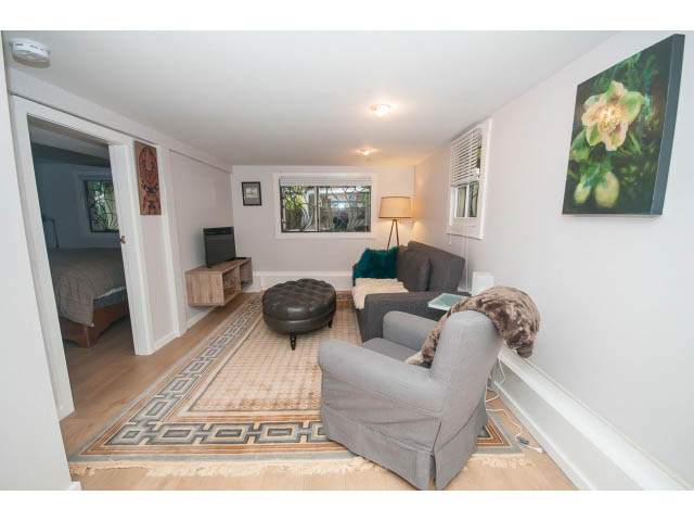 Bright living room with patterned rug, modern furniture, and large artwork on the wall. - Suite - 817 Union St, Vancouver East Side