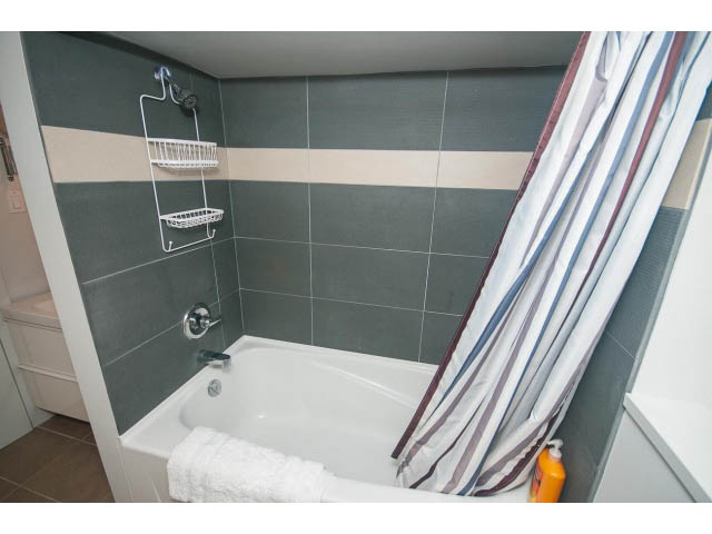Bathroom with bathtub, shower, and striped curtain. - Suite - 817 Union St, Vancouver East Side
