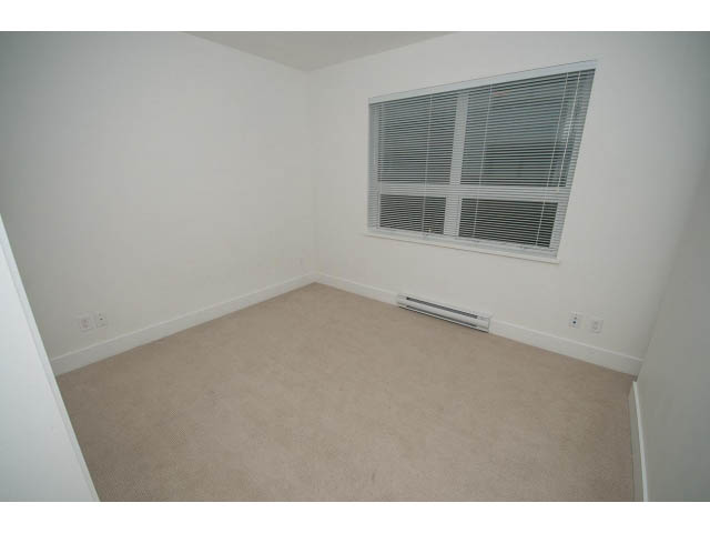 Bright living room with beige carpet and white walls, featuring a large window with blinds. - 9 - 3508 Mount Seymour Pkwy, North Vancouver