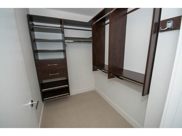 Spacious walk-in closet with wooden shelves and drawers, clean white walls. - 9 - 3508 Mount Seymour Pkwy, North Vancouver