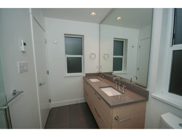 Modern bathroom with wooden cabinets and a large mirror. - 9 - 3508 Mount Seymour Pkwy, North Vancouver