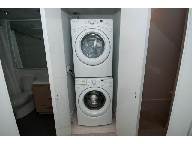Bright laundry room with white appliances and wooden cabinets. - 9 - 3508 Mount Seymour Pkwy, North Vancouver