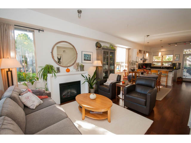 Spacious living room with hardwood floors, modern furniture, and a city view through large windows. - 4539 Prince Albert Street, Vancouver East Side