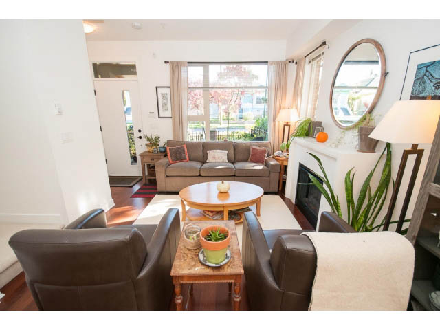 Furnished living room with hardwood floors, large windows, and a cozy sofa. - 4539 Prince Albert Street, Vancouver East Side