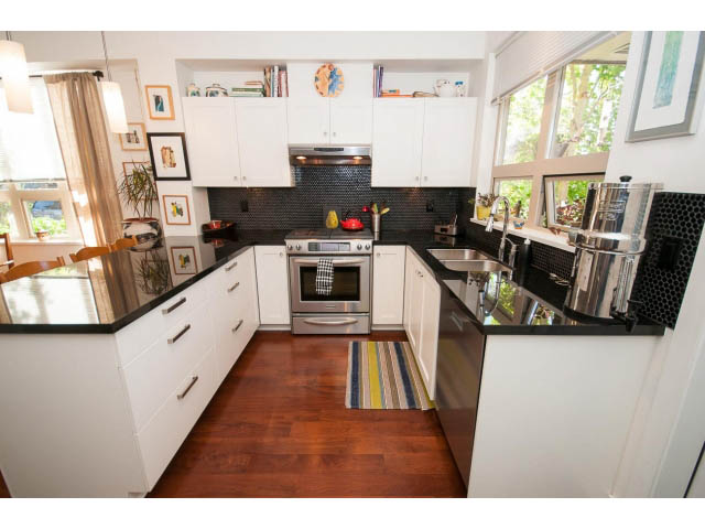 Bright kitchen with white cabinets, black countertops, and hardwood floors. - 4539 Prince Albert Street, Vancouver East Side