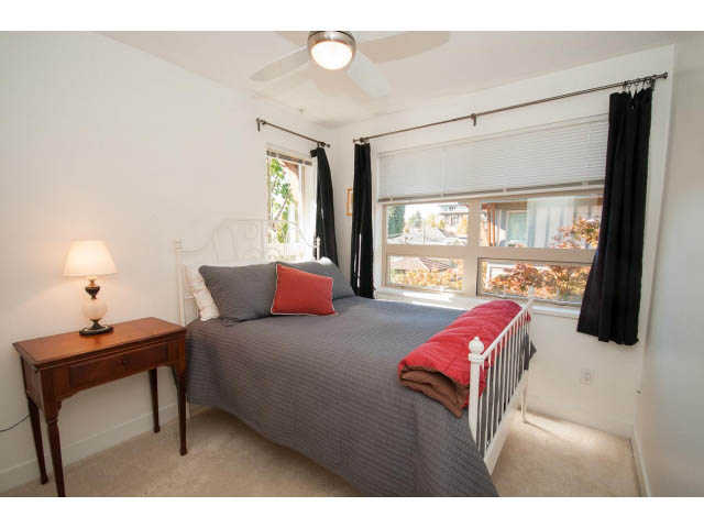 Furnished bedroom with large window, natural light, and cozy bedding. - 4539 Prince Albert Street, Vancouver East Side