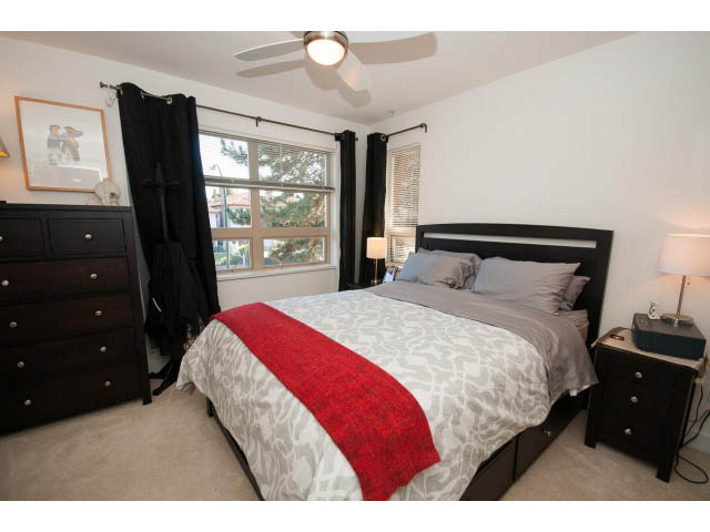 Furnished bedroom with a large bed, red throw, and dark wood furniture. - 4539 Prince Albert Street, Vancouver East Side