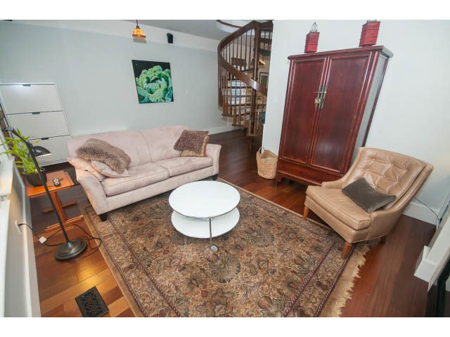 Spacious living room with hardwood floors, spiral staircase, and large armoire. - Upper - 817 Union St, Vancouver East Side