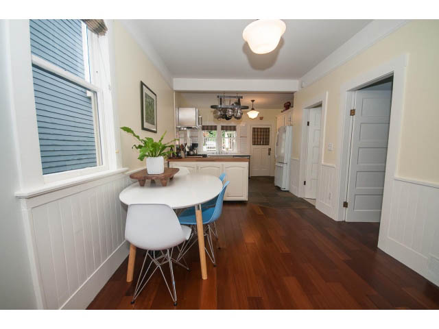 Bright dining area with white cabinets, hardwood floors, and a view of the kitchen. - Upper - 817 Union St, Vancouver East Side
