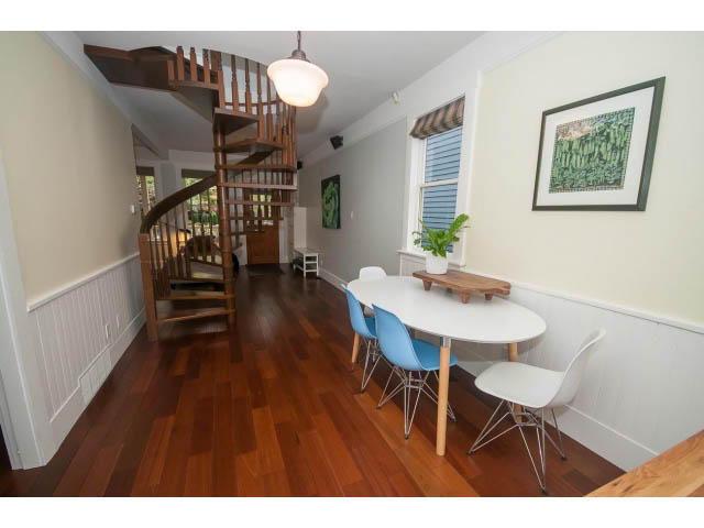 Bright dining area with white countertops, hardwood floors, and a spiral staircase leading to the upper level.