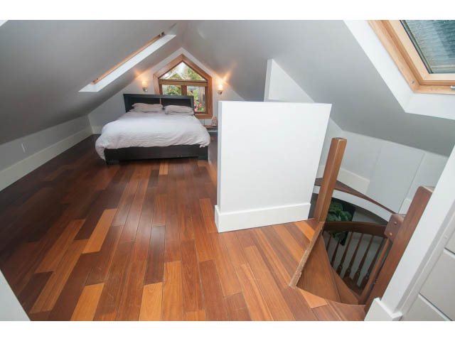 Bright loft bedroom with hardwood floors and a sloped ceiling, featuring a cozy bed and a small window. - Upper - 817 Union St, Vancouver East Side