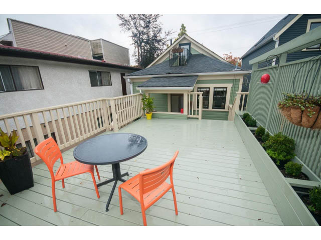 Furnished patio with orange chairs and greenery, leading to a shared house with 2 bedrooms. - Upper - 817 Union St, Vancouver East Side