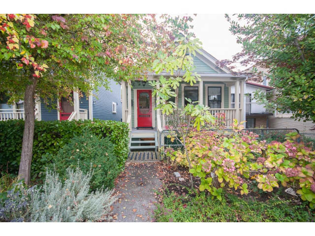 Bright and cozy living room with a red door and wooden porch, surrounded by autumn foliage. - Upper - 817 Union St, Vancouver East Side