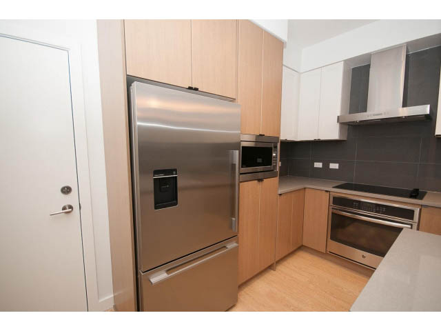 Bright kitchen with stainless steel appliances, light wood cabinets, and white countertops. - 410 - 3205 Mountain Hwy, North Vancouver
