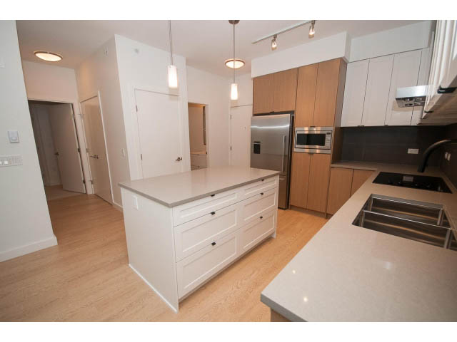 Bright kitchen with white cabinets, granite countertops, and hardwood floors. - 410 - 3205 Mountain Hwy, North Vancouver
