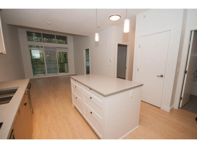 Bright kitchen with white cabinetry, hardwood floors, and a city view. - 410 - 3205 Mountain Hwy, North Vancouver