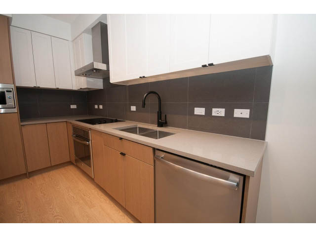Bright kitchen with light wood cabinets, dark backsplash, and stainless steel appliances. - 410 - 3205 Mountain Hwy, North Vancouver