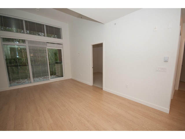 Bright living room with hardwood floors and sliding glass doors. - 410 - 3205 Mountain Hwy, North Vancouver