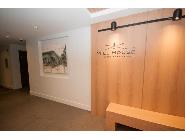 Foyer with wooden paneling and "Mill House" sign, modern lighting. - 410 - 3205 Mountain Hwy, North Vancouver