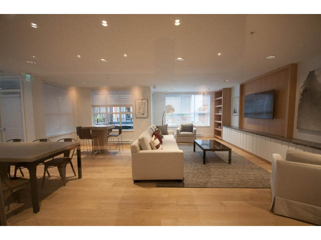 Spacious living room with hardwood floors, large windows, and modern furnishings. - 410 - 3205 Mountain Hwy, North Vancouver