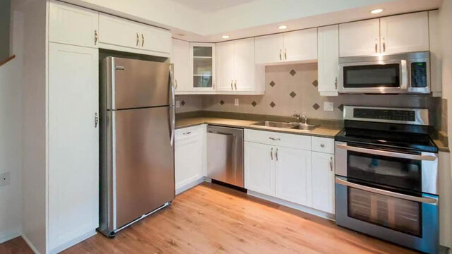 Kitchen with white cabinetry, stainless steel appliances, and light hardwood flooring. - 13-870 West 7th Avenue, Vancouver West Side