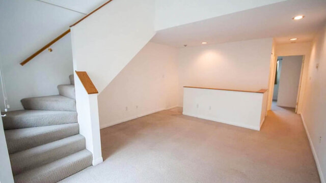 Open living area with carpeted staircase, wooden handrail, and a wood-topped partition wall. - 13-870 West 7th Avenue, Vancouver West Side
