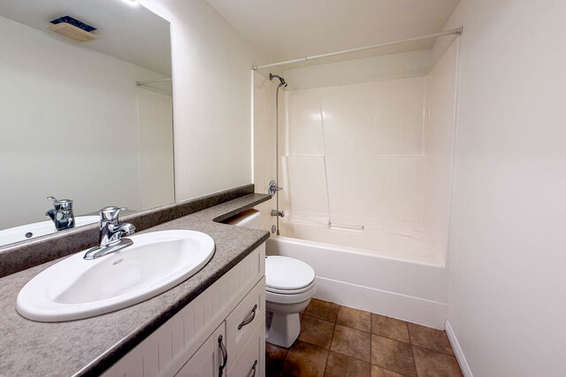 Main bathroom with white vanity and oval sink, large mirror, toilet and a tub with shower. - 13-870 West 7th Avenue, Vancouver West Side