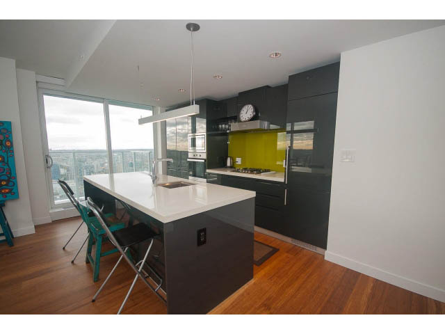 Bright kitchen with modern black cabinetry, white countertops, hardwood floors, and a city view. - 4609 - 777 Richards St, Vancouver Downtown