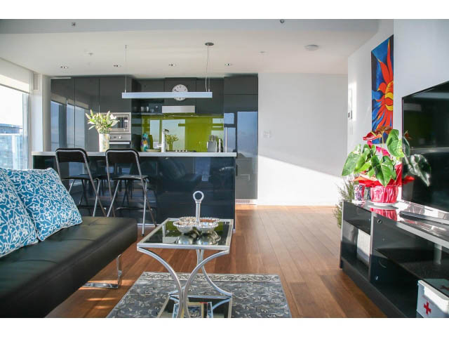 Open-concept living space with modern furnishings, hardwood floors, and a kitchen with green countertops. - 4609 - 777 Richards St, Vancouver Downtown