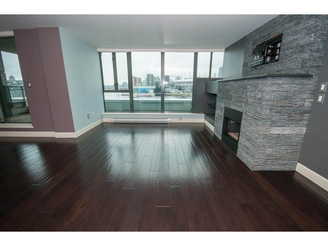 Spacious living room with hardwood floors, city view, and stone fireplace. - 706 - 1088 Quebec St., Vancouver East Side