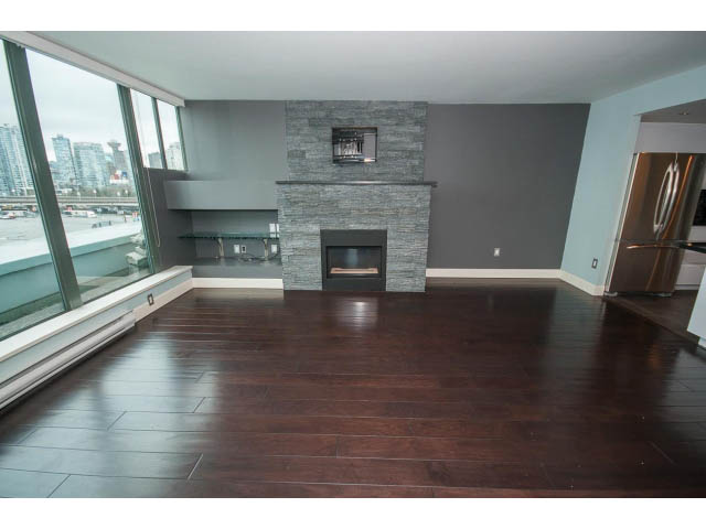 Spacious living room with hardwood floors, city view, and modern fireplace. - 706 - 1088 Quebec St., Vancouver East Side