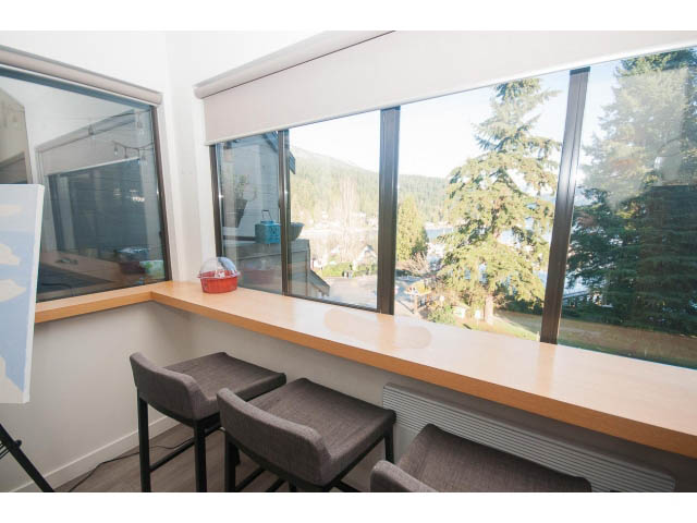 Bright kitchen with large windows offering a scenic view of the mountains and trees, featuring wooden countertops and bar...