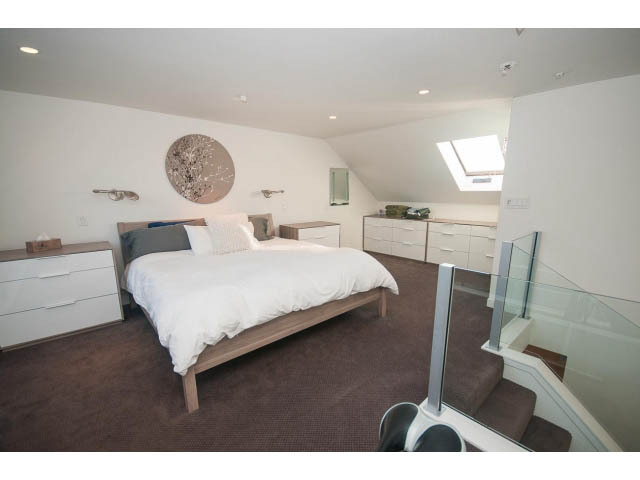 Bright bedroom with modern furnishings, large window, and sleek white cabinetry. - 15 - 2151 Banbury Rd, North Vancouver