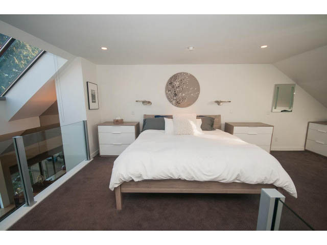 Spacious bedroom with modern decor, large bed, and glass railing. - 15 - 2151 Banbury Rd, North Vancouver