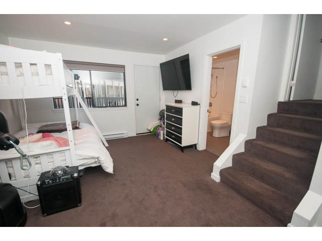 Bright living room with a large TV, bunk bed, and carpeted stairs leading to the bedrooms. - 15 - 2151 Banbury Rd, North Vancouver