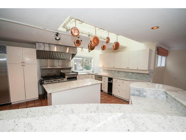 Bright kitchen with granite countertops, stainless steel appliances, and copper pots hanging above. - 4220 Starlight Way, North Vancouver