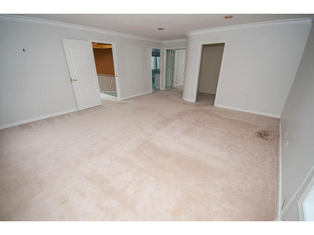 Spacious living room with beige carpet and white walls, leading to another room. - 4220 Starlight Way, North Vancouver