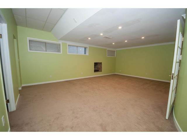 Spacious living room with light green walls and beige carpeting. - 4220 Starlight Way, North Vancouver