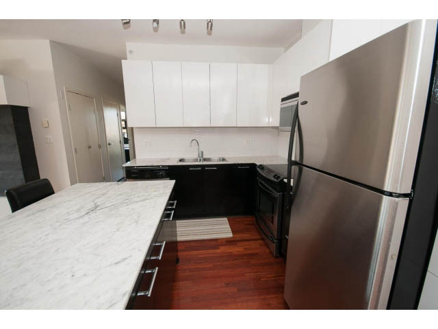 Bright kitchen with white cabinets, granite countertops, and hardwood floors. - 401 - 2828 Yew St, Vancouver West Side