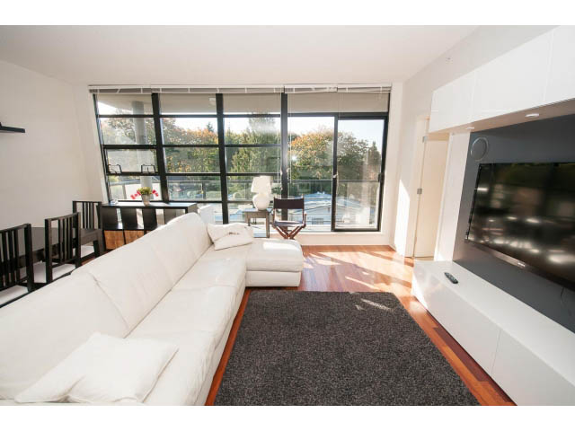Spacious living room with large windows, hardwood floors, and a modern fireplace. - 401 - 2828 Yew St, Vancouver West Side