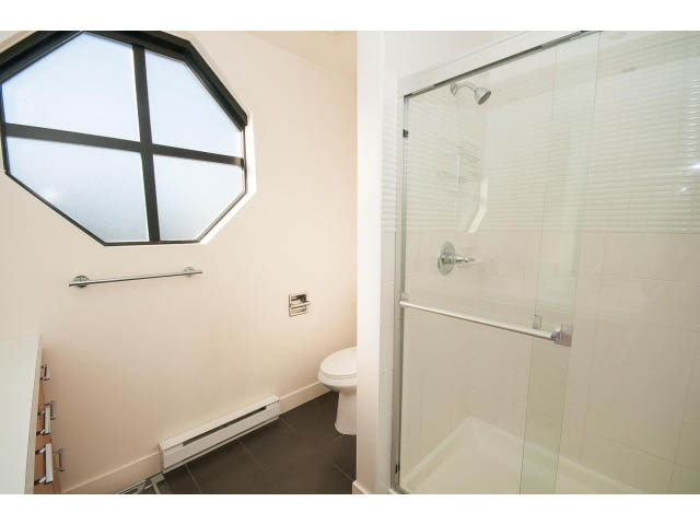 Bright bathroom with octagonal window and glass shower door. - 401 - 2828 Yew St, Vancouver West Side